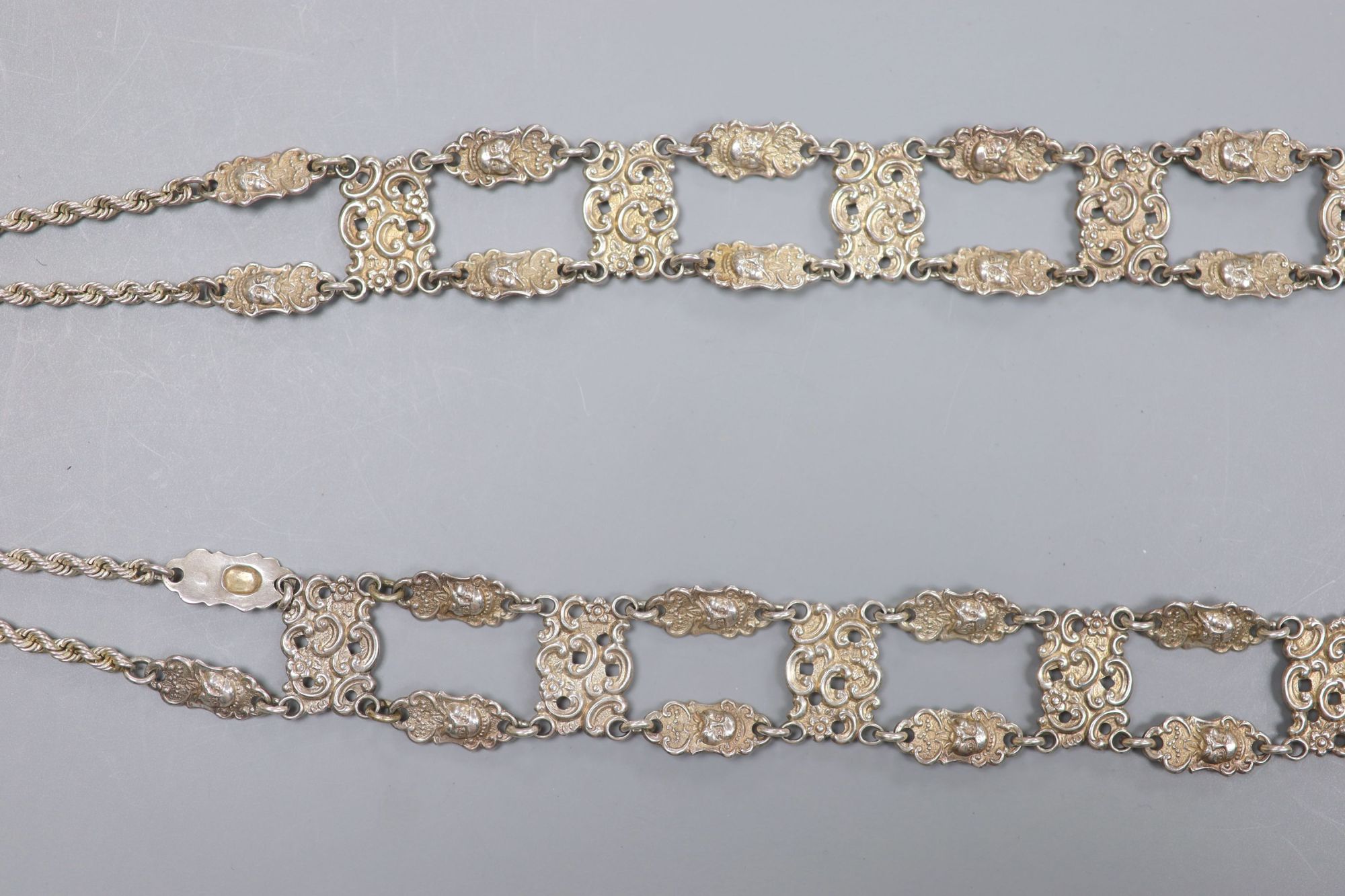 An Edwardian long silver ropetwist chain and openwork panel tassel necklace, with mask decoration